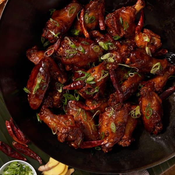 Shlap Muan chicken wings, glazed with sauce, garnished with green onions and dried red chilies.