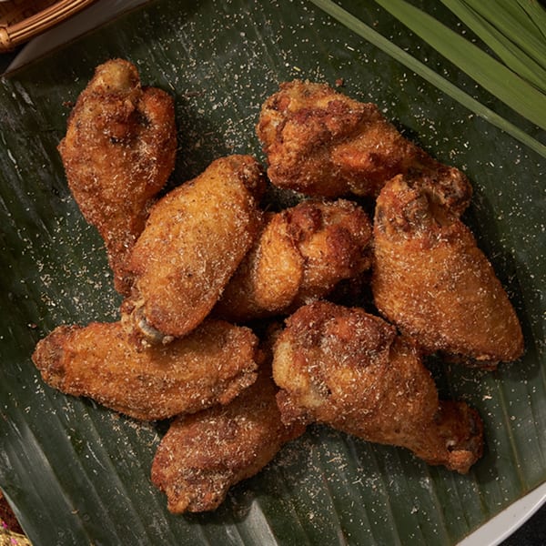 Shlap Muan Chicken Wings, crispy fried wings seasoned with spices, served on a banana leaf.